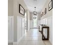 Inviting foyer boasts neutral walls, white wainscoting, tile floors, stylish console table, and decorative wall art at 13130 Monach Isles Dr, Riverview, FL 33579