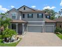 Charming two-story home featuring a three-car garage, brick paved driveway, and tropical landscaping at 13311 Orca Sound Dr, Riverview, FL 33579