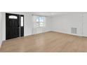 Bright living room with wood-look tile flooring, large windows, and a modern front door at 13612 Veronica Dr, Hudson, FL 34667