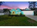 Inviting home featuring a manicured lawn and vibrant exterior, all set against a colorful dusk sky at 1709 Sunset Dr, Tarpon Springs, FL 34689