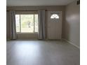 Bright living room features new flooring, a large window with curtains, and a white door, ready for personal touches at 2360 World Parkway Blvd # 36, Clearwater, FL 33763