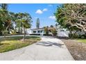 Inviting single-story home featuring lush landscaping, a circular driveway, and a well-maintained facade at 3555 Belle Vista E Dr, St Pete Beach, FL 33706