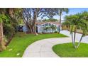 Lovely home featuring a long drive way, vibrant landscaping, palm trees, and unique architectural details at 425 12Th Ave, Indian Rocks Beach, FL 33785