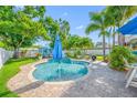 Beautiful backyard with a kidney-shaped pool, paver patio, lounge chairs, and a blue umbrella for shade at 4721 W Lawn Ave, Tampa, FL 33611