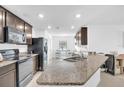 Modern kitchen featuring granite countertops, stainless steel appliances, and dark wood cabinetry at 7099 Crested Orchid Dr, Brooksville, FL 34602