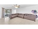 Spacious living room featuring a large sectional sofa, tile flooring, and lots of natural light at 7099 Crested Orchid Dr, Brooksville, FL 34602