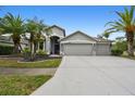 Beautiful home featuring a three-car garage, stone accents, and lush tropical landscaping at 8208 Pinewood Run Ct, Tampa, FL 33647