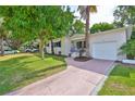 Inviting home featuring a lush lawn and mature trees, plus a driveway leading to an attached garage at 913 Chester Dr, Clearwater, FL 33756