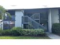 Exterior view of the condo featuring stair access, verdant landscaping, and a well-maintained lawn at 11201 122Nd Ave # 103, Largo, FL 33778