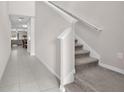 Inviting hallway features tile flooring and a staircase with carpeted steps at 12715 Maple Bonsai Dr, Riverview, FL 33579