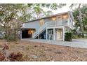 Two-story home with carport and exterior staircase leading to the living area, surrounded by lush greenery at 138 69Th N Ave, St Petersburg, FL 33702