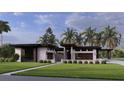 Modern home showcasing a symmetrical design, separate garages, and beautifully maintained landscaping with mature palm trees at 19211 Gunn Hwy, Odessa, FL 33556