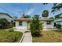 Cozy single-story home with a sidewalk, shuttered windows, an American flag, and a well-maintained lawn at 306 Banana St, Tarpon Springs, FL 34689