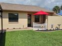 Cozy single-story home with a well-manicured lawn, decorative white picket fence, and a bright red umbrella at 38225 Ironwood Pl # 38225, Zephyrhills, FL 33542