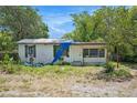 Exterior view of a weathered single-story home with a blue tarp on the roof at 4815 N Falkenburg Rd, Tampa, FL 33610
