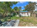 Back of single story home with white paint, weeds, partial fence and tree coverage at 4815 N Falkenburg Rd, Tampa, FL 33610