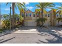 Lovely tan townhome showcasing beautiful palm trees and a brick-paved driveway at 789 Grand Cypress Ln, Tarpon Springs, FL 34689