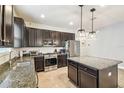Modern kitchen with dark cabinets, granite countertops, and stainless steel appliances at 8228 Sunlit Horizon Ln, Land O Lakes, FL 34637