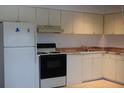 Traditional kitchen with white cabinets, laminate countertops, and a standard appliance package at 11447 Park Blvd # 301, Seminole, FL 33772