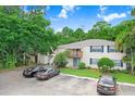 Two-story condo building with yellow siding, blue shutters, and a parking area with parked cars at 134 Sycamore Ln # F, Oldsmar, FL 34677