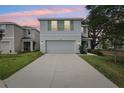 Two-story home featuring a two-car garage, tidy lawn, and charming green shutters at dusk at 36557 Night Strawberry Ct, Dade City, FL 33525