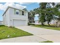 View of home featuring a two-car garage, lawn, and mature tree at 36557 Night Strawberry Ct, Dade City, FL 33525