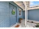 Inviting blue home entrance with a decorative wreath, potted plants, and a welcoming covered porch at 4516 W Paxton Ave, Tampa, FL 33611