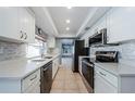 Bright kitchen featuring white cabinetry, stainless steel appliances, and mosaic backsplash at 4704 Shale Pl, Tampa, FL 33615