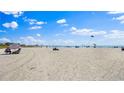 Wide sandy beach with scattered beachgoers enjoying sunny weather with blue skies and white clouds at 6700 Sunset Way # 206, St Pete Beach, FL 33706
