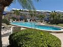 Exterior community pool featuring comfortable seating, landscaping, and lounge chairs at 6700 Sunset Way # 206, St Pete Beach, FL 33706