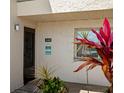 Condo entrance featuring unit number, a decorative sign, and tropical plants, creating a welcoming outdoor foyer at 7701 Starkey Rd # 443, Seminole, FL 33777