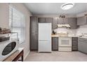 Compact kitchen with white appliances, grey cabinets, and a bright window for natural light at 8703 Bardmoor Blvd # 305, Seminole, FL 33777
