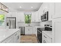 Modern kitchen featuring stainless steel appliances, white cabinetry, and stone countertops at 8906 N Otis Ave, Tampa, FL 33604