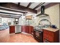 Rustic kitchen featuring wood beams, terracotta floors, stainless steel appliances and decorative brick surrounding the stove at 1039 Union St, Clearwater, FL 33755