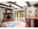 Living room showcasing a brick fireplace, beamed ceiling, and access to an outdoor screened-in lanai with a fountain at 1039 Union St, Clearwater, FL 33755