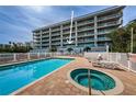 Relaxing pool and jacuzzi area with lounge chairs and condo in the background at 19519 Gulf Blvd # 203, Indian Shores, FL 33785