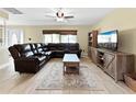 Comfortable living room featuring neutral walls, tile floors, ceiling fan, and large leather sectional at 3508 Yale Cir, Riverview, FL 33578