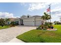 Lovely single-story home with a three-car garage, paver driveway, manicured lawn and an American flag at 3727 Wild Blossom Pl, Parrish, FL 34219