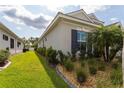 Side yard featuring lush green grass, tropical plants and shrubs, rock landscaping, and a home exterior at 3727 Wild Blossom Pl, Parrish, FL 34219
