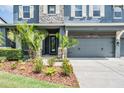 Close-up of the home's exterior with well-manicured landscaping, decorative shutters, and a two-car garage at 4094 Windcrest Dr, Wesley Chapel, FL 33544