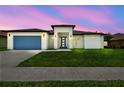 Beautiful home at dusk, featuring a blue garage door, modern design, and lush green lawn at 4260 Baudelaire Ct, Brooksville, FL 34604