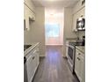 Galley kitchen with white cabinets, stainless steel appliances, and wood-look flooring at 7526 Needle Leaf Pl # 29, Tampa, FL 33617