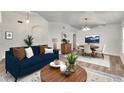 This staged living room features a blue sofa, wood floors, and a dining area set for four at 10048 Creek Bluff Dr, Riverview, FL 33578