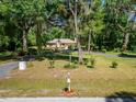 A single-story home surrounded by lush greenery and mature trees, showcasing the expansive front yard at 11120 Lu Wista Ln, Brooksville, FL 34601