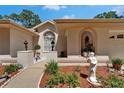 Inviting front entrance with lush landscaping, a decorative window, and a charming walkway at 11120 Lu Wista Ln, Brooksville, FL 34601