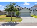 Inviting single-Gathering home featuring a stone facade, well-maintained lawn, and an attached two-car garage at 11831 Thicket Wood Dr, Riverview, FL 33579
