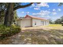 Three-car garage featuring a red roof, located in a large, tree-lined yard at 1202 Williams Rd, Plant City, FL 33565