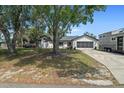Exterior view of single-story home with lush greenery and spacious driveway with an attached two car garage at 12493 Fish Cove Dr, Spring Hill, FL 34609