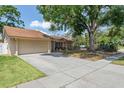 Well-kept single-story home featuring an attached garage and mature trees at 12606 Rain Forest St, Temple Terrace, FL 33617