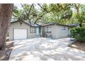 Spacious driveway leading to a single-car garage, surrounded by lush greenery at 1310 Hilton Pl, Tampa, FL 33604